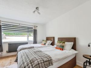 two beds in a bedroom with a window at Mylnebeck Lodge in Windermere