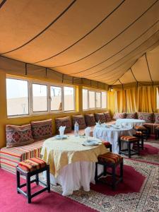 a tent room with tables and couches and windows at Le Pacha Luxury Desert Camp - Mhamid Sahara Activities in Mhamid +58 photos