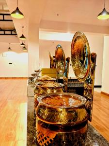 a row of gold dishes on a counter in a room at HOTEL FORTUNER Inn in Bangalore