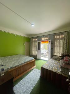 a green bedroom with two beds and a window at Jojos homestay in Mirik