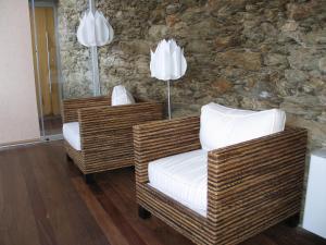 two wicker chairs in a room with a stone wall at Quinta dos Castanheiros - Turismo Rural in Negreda