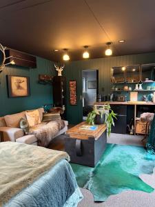 a living room with green walls and a bed and a table at The Olde Whiskey Room in Queenstown