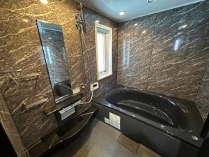a bathroom with a black tub and a mirror at Chalet Yutaka in Furano