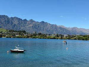 two boats on a lake with mountains in the background at The Olde Whiskey Room in Queenstown