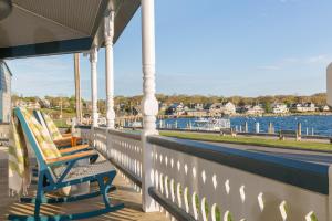 una fila de sillas sentadas en un porche con vistas al agua en Summercamp, en Oak Bluffs