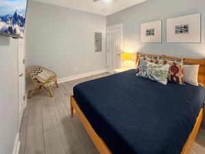 a bedroom with a bed with blue sheets and a chair at Live Oak Cottage OKI Beach Retreat in Oak Island