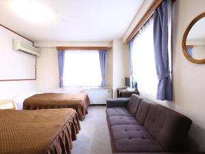 a room with two beds and a couch and a mirror at Hotel Sunplaza Tsugaike in Otari