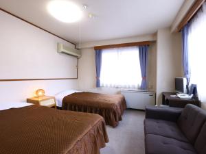 a hotel room with two beds and a couch at Hotel Sunplaza Tsugaike in Otari