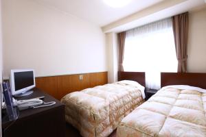 a hotel room with two beds and a computer on a desk at Hotel Sunplaza Tsugaike in Otari
