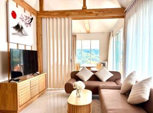a living room with a couch and a tv at Japanese house PhuSaimorkVilla in Ban Kai Noi