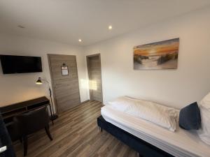 a bedroom with a bed and a desk and a television at Hotel Zur Post in Haren