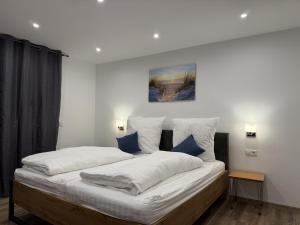 a large bed with white sheets and blue pillows at Hotel Zur Post in Haren