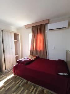 a red bed in a room with a window at Ibiza beach apartments in Alexandria