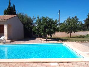 a blue swimming pool in front of a house at Beautiful holiday home in Argeliers with pool in Argeliers