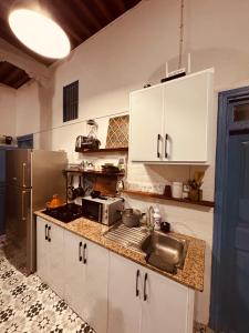 a kitchen with white cabinets and a sink and a microwave at essaouira van hostel in Essaouira