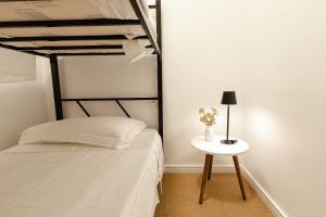 a bedroom with a bed and a table with a lamp at P&G Apto 203-Bagnoregio in Caxias do Sul