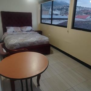 a bedroom with a bed and a table and window at Departamento MEDIO DIA in Quito +5 photos
