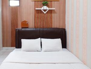 a bed with a black headboard and white pillows at Roemah Djogja Inn Seturan Raya RedPartner in Seturan