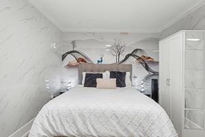 a bedroom with a large bed with white walls at Secluded Bachelor Suite in Vancouver
