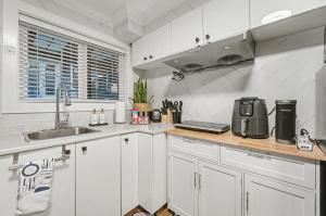 a kitchen with white cabinets and a sink at Secluded Bachelor Suite in Vancouver