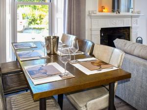 a wooden table with wine glasses and a couch at Cedars in Mortehoe