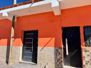an orange building with a black door and windows at Departamento Cómodo y Accesible in Humahuaca