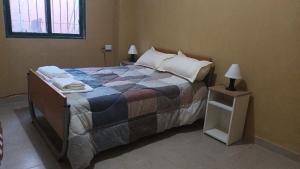 a bedroom with a large bed and a night stand at Departamento Cómodo y Accesible in Humahuaca