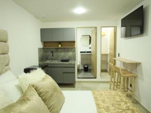 a bedroom with a white bed and a kitchen at Santa Barbara Central Suites in Bogotá