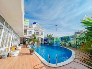 a large building with a swimming pool in a courtyard at Phong Dung Beach Hotel Phan Ri Cua in Tuy Phong