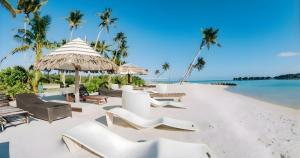 a beach with chairs and umbrellas and the ocean at Dhiggaa by H Collection in Huraa