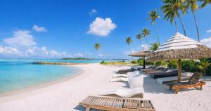 a beach with chairs and umbrellas and the ocean at Dhiggaa by H Collection in Huraa +39 photos