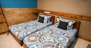 two beds in a bedroom with blue and white comforter at Dhiggaa by H Collection in Huraa