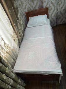 a small bed with white sheets and a curtain at Karimbek Guest house by SamApart in Samarkand