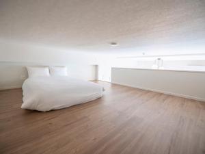 a white bedroom with a bed and a wooden floor at Hotel Tomas Asahibashi Station in Naha +15 photos