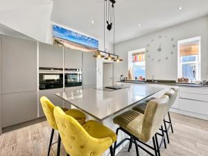 a kitchen with a dining table and yellow chairs at Cedars in Mortehoe
