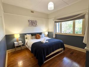 a bedroom with a bed with a blue blanket and a window at 5-Bed Secret Garden House in Croydon