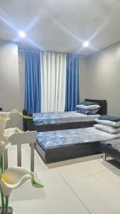 two beds in a room with blue curtains at The Highland Condotel in Baguio
