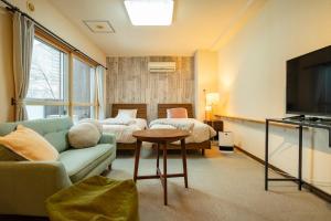 a living room with a couch and a bed and a television at Fewdays Condominium108 in Sapporo