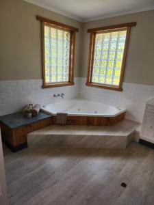 a large bath tub in a bathroom with two windows at Kentish Hills Retreat in Sheffield