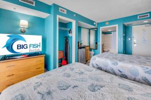 a bedroom with two beds and a blue wall at Oceanfront,Heated Pools,Boardwalk, Location,Views! in Myrtle Beach