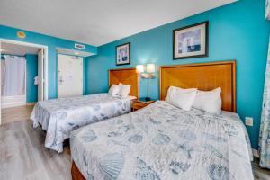 two beds in a hotel room with blue walls at Oceanfront,Heated Pools,Boardwalk, Location,Views! in Myrtle Beach