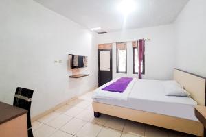 a white bedroom with a bed and a tv at Villa Citra Syariah RedPartner in Kalibata 1