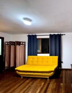 a yellow couch in a room with blue curtains at Avaroa 350 express in Sucre