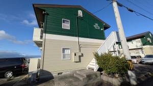 a green and white house with a car parked in a parking lot at 牟礼ぐらし宿 in Takamatsu