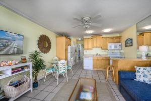 a living room with a blue couch and a kitchen at Oceanfront 1BR • Top-Floor Balcony Views • Cherry Grove • Sea Cabin 304-A in Myrtle Beach
