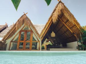 a resort with a thatched roof and a pool at Vibes Villas Siargao in General Luna