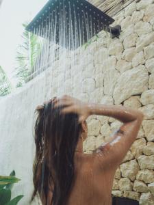 a woman bathing in a shower in front of a waterfall at Vibes Villas Siargao in General Luna +33 photos