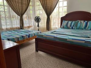 a bedroom with two beds and windows with curtains at Casa Campestre Kostal Azul in Tocaima +12 photos