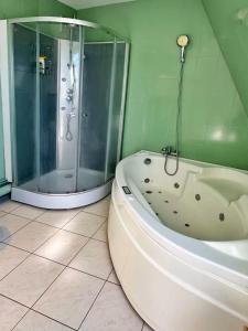 a bathroom with a shower and a white bath tub at Duplex with Jacuzzi and parking Close to Disney in Lognes +22 photos