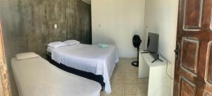 a small room with two beds and a television at Quarto na Atalaia in Aracaju